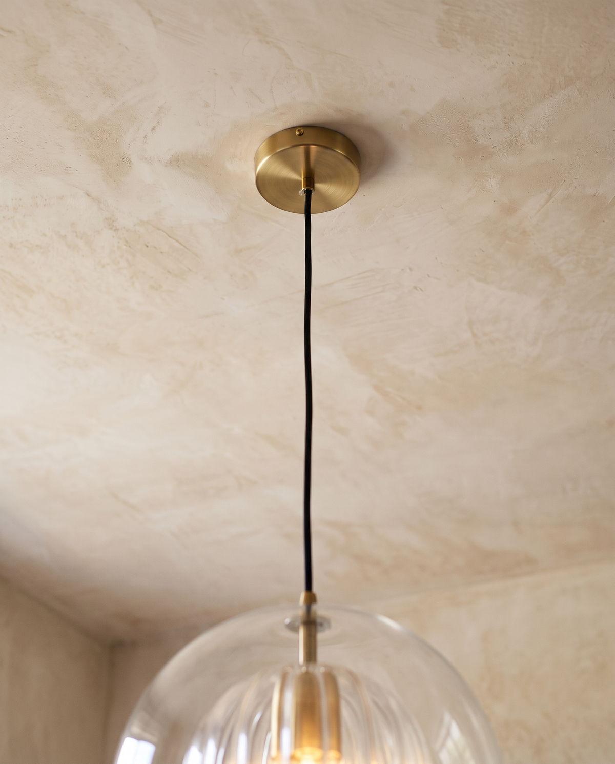 The brass-finish ceiling rose and black cord of The Nest