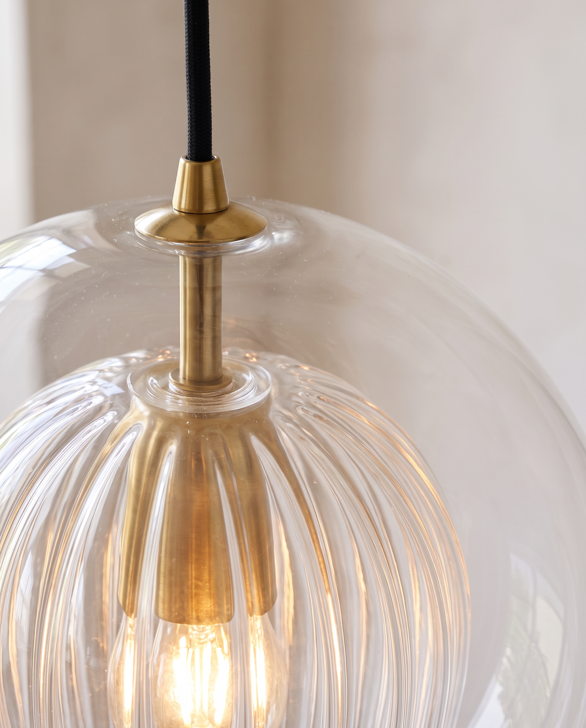 Close-up of the ribbed inner glass and brass-finish holder of The Nest