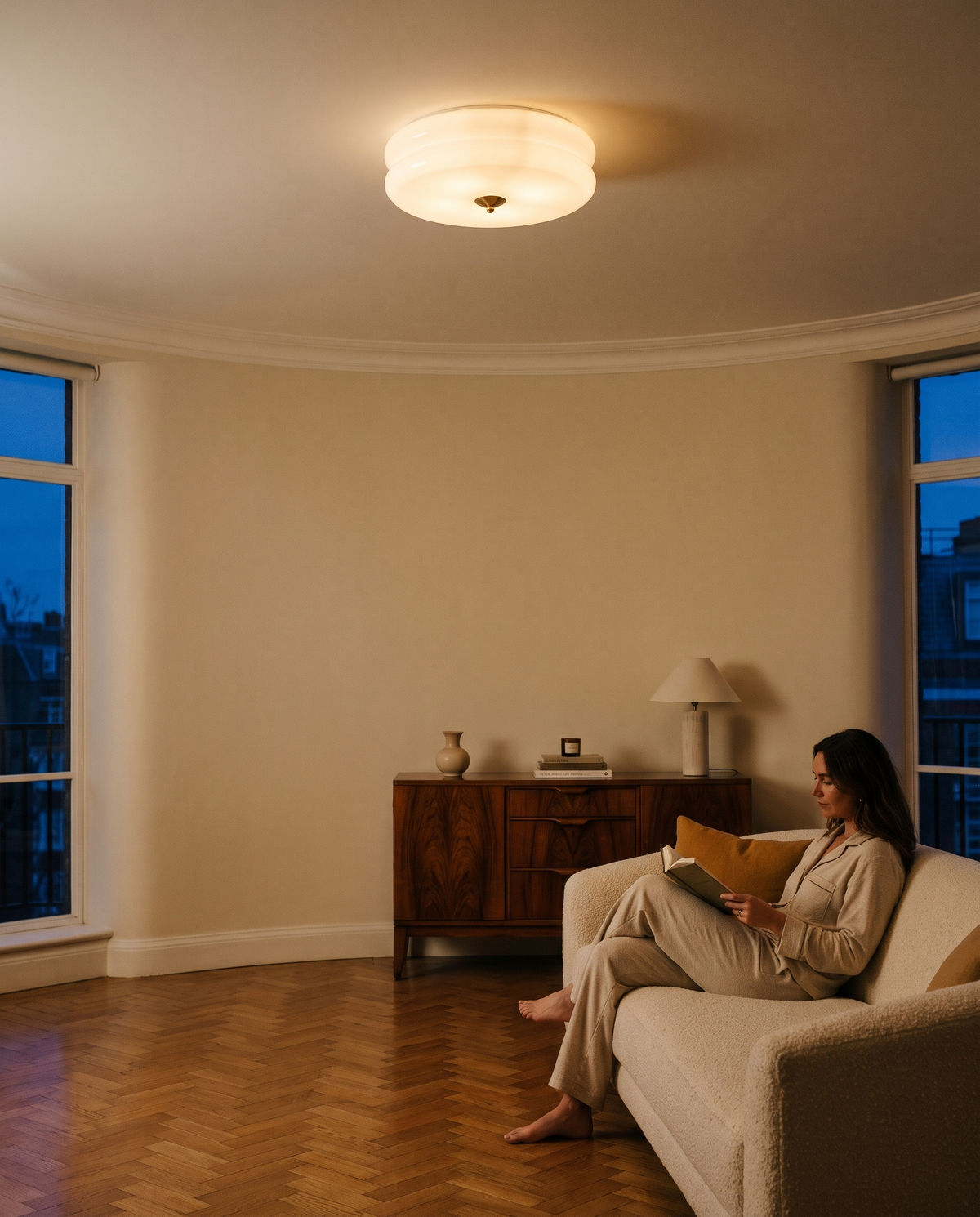 A woman reading on a bouclé sofa under The Odeon in a mansion flat