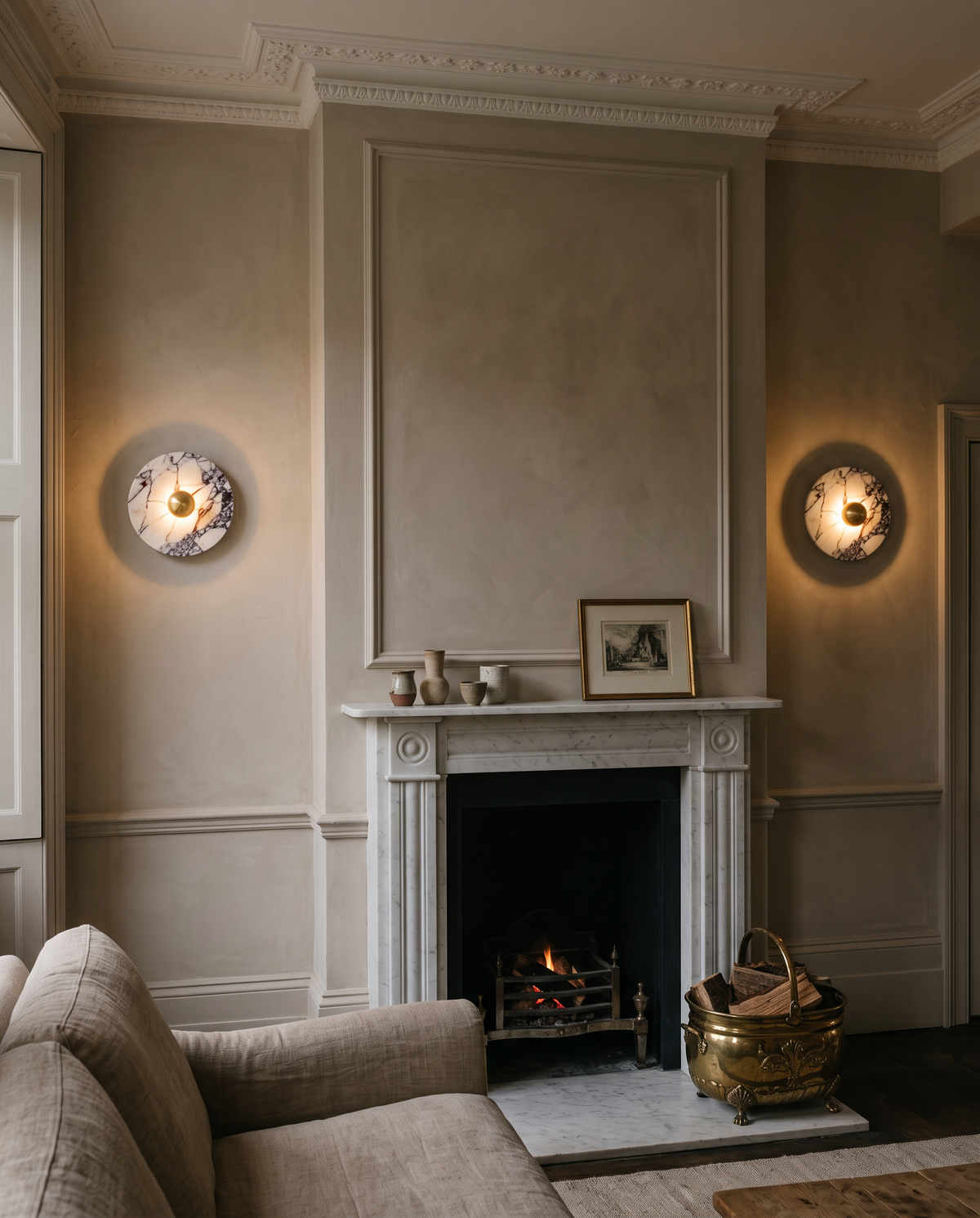 A pair of Orb marble wall lights in brass either side of a Georgian fireplace