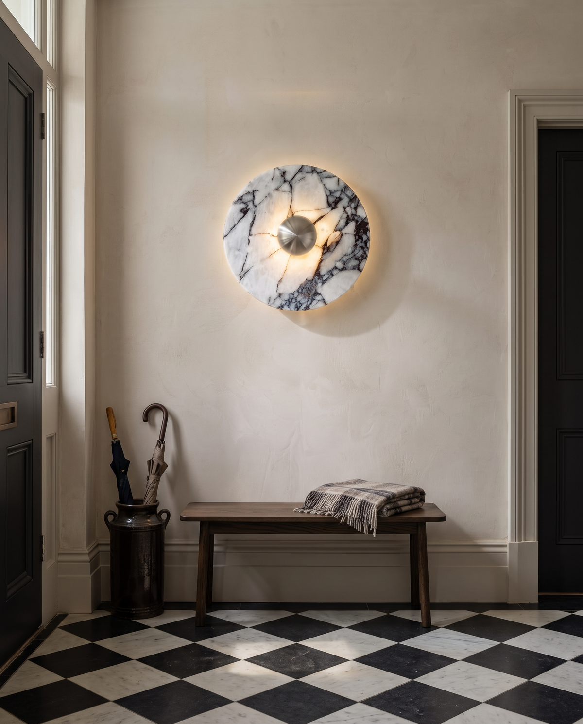 The Orb marble wall light in silver above a bench in a chequerboard hallway