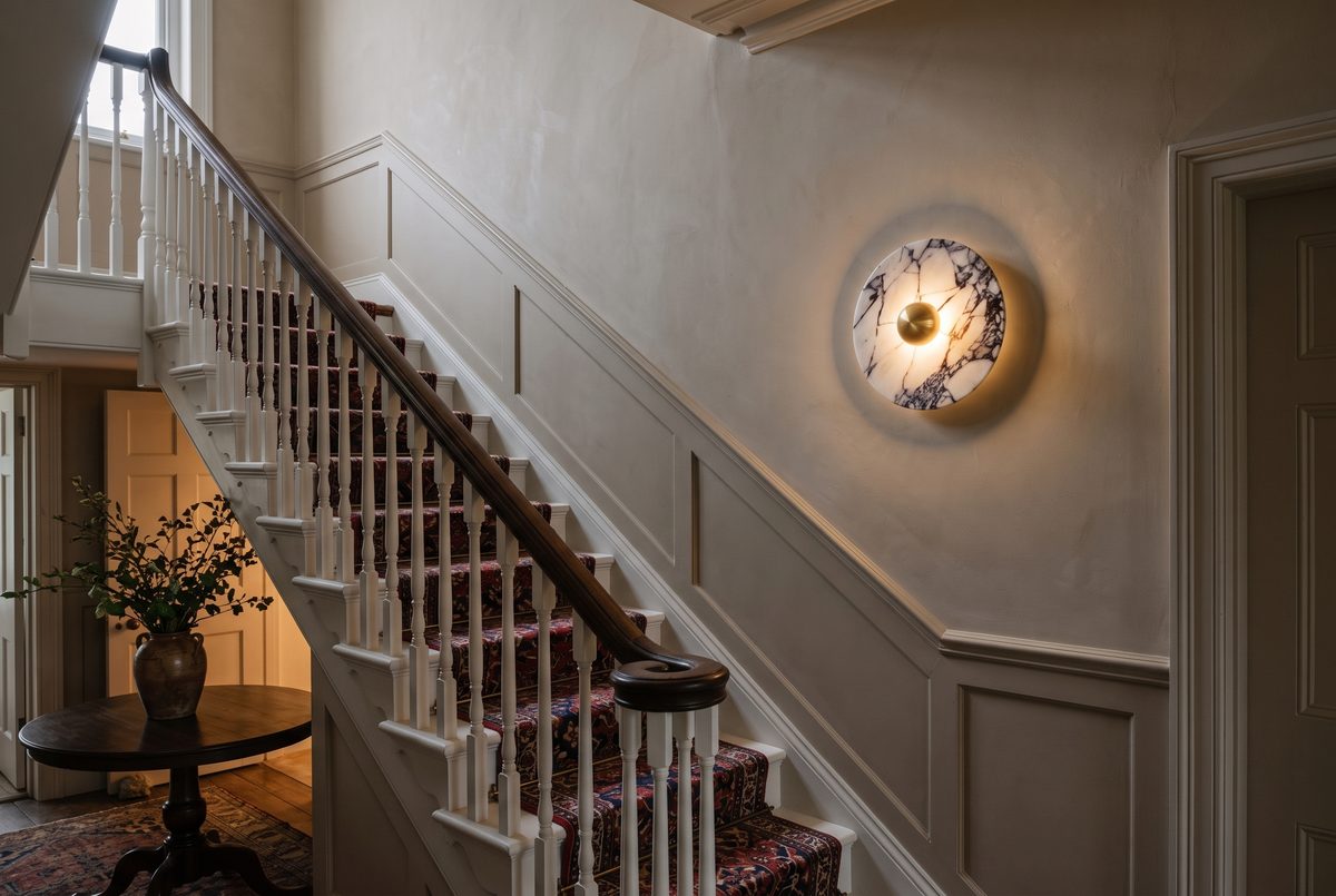 The Orb marble wall light in brass in a staircase hall
