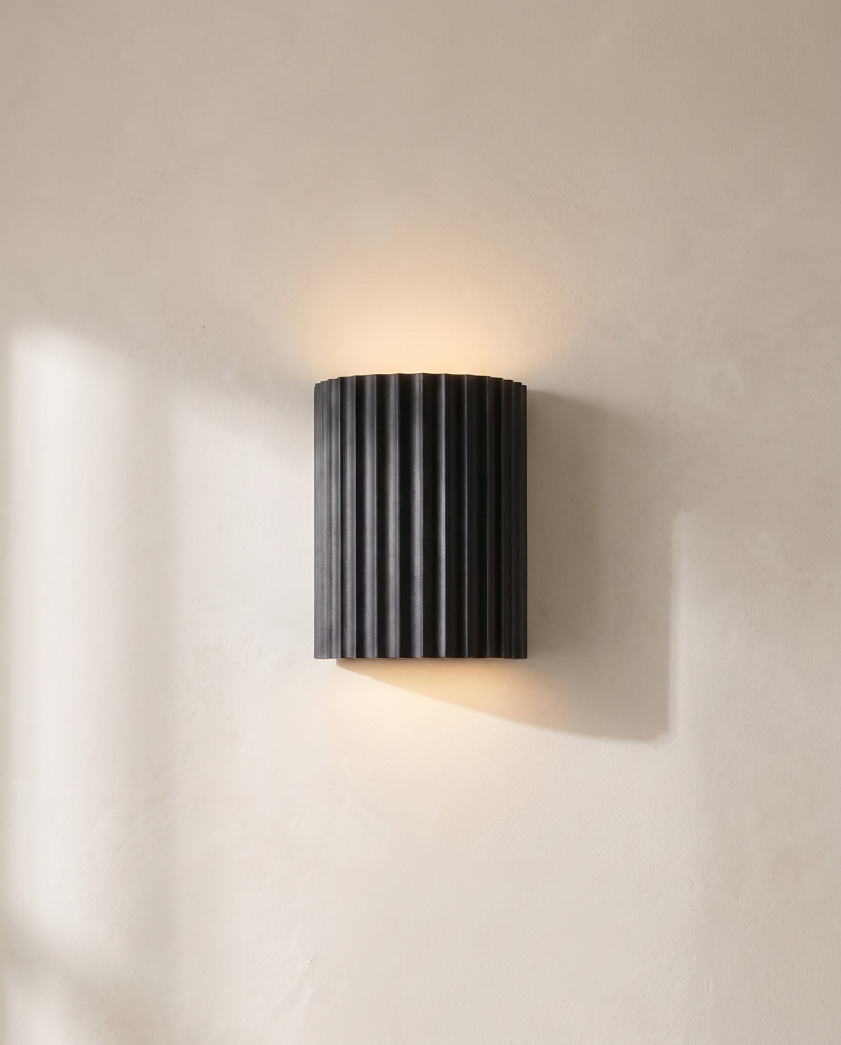 The Pleat, dark grey fluted wall light in situ on lime-washed plaster wall — Selden Home product photography