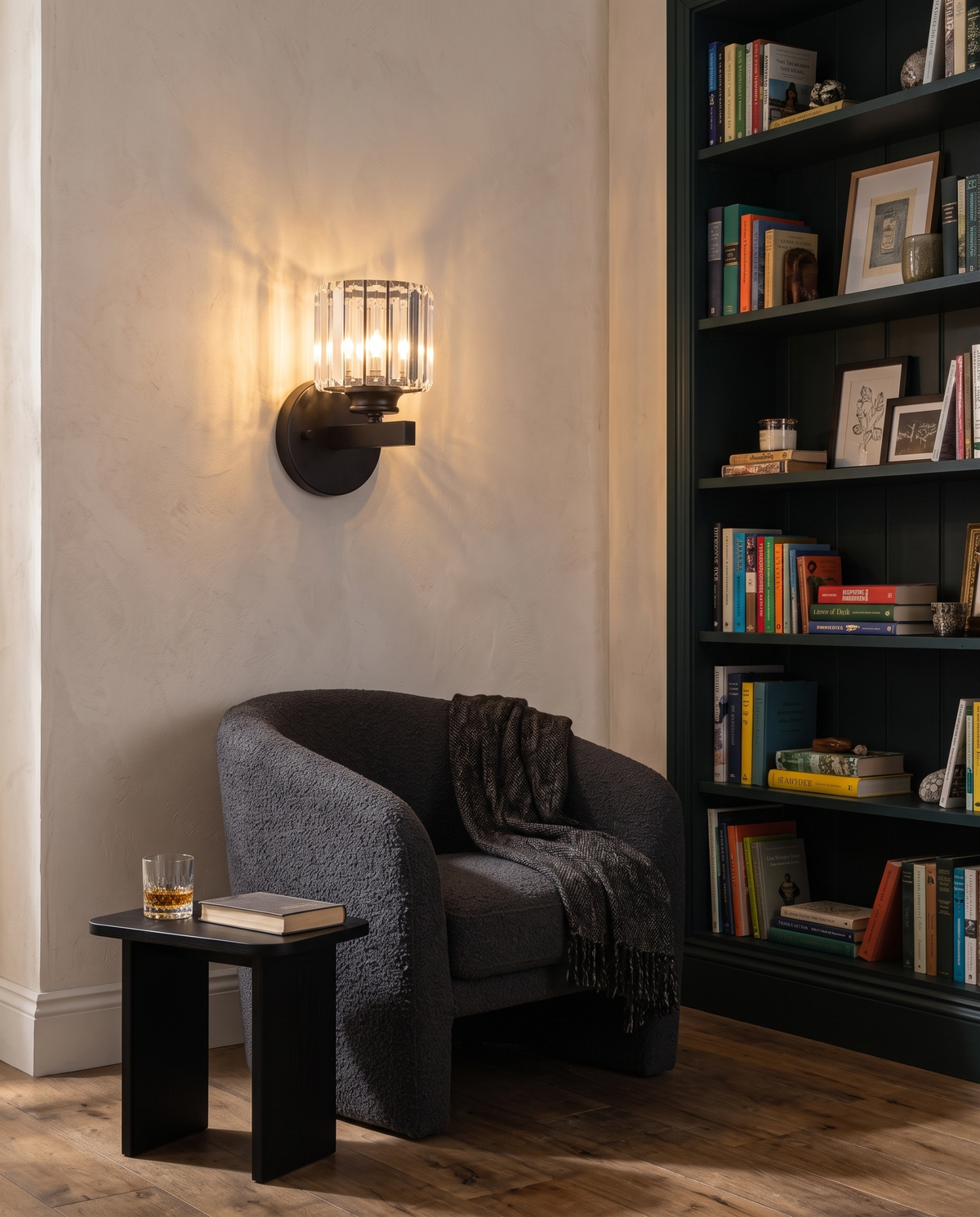 The Prism crystal wall sconce in black above a boucle armchair