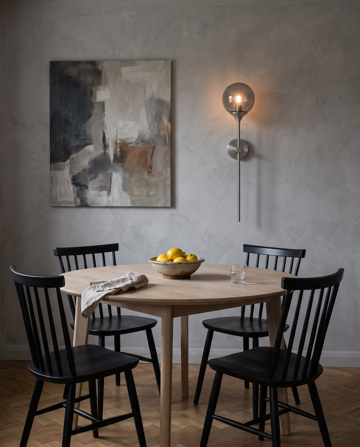 The Reed wall sconce in silver with a smoke grey globe beside a round dining table