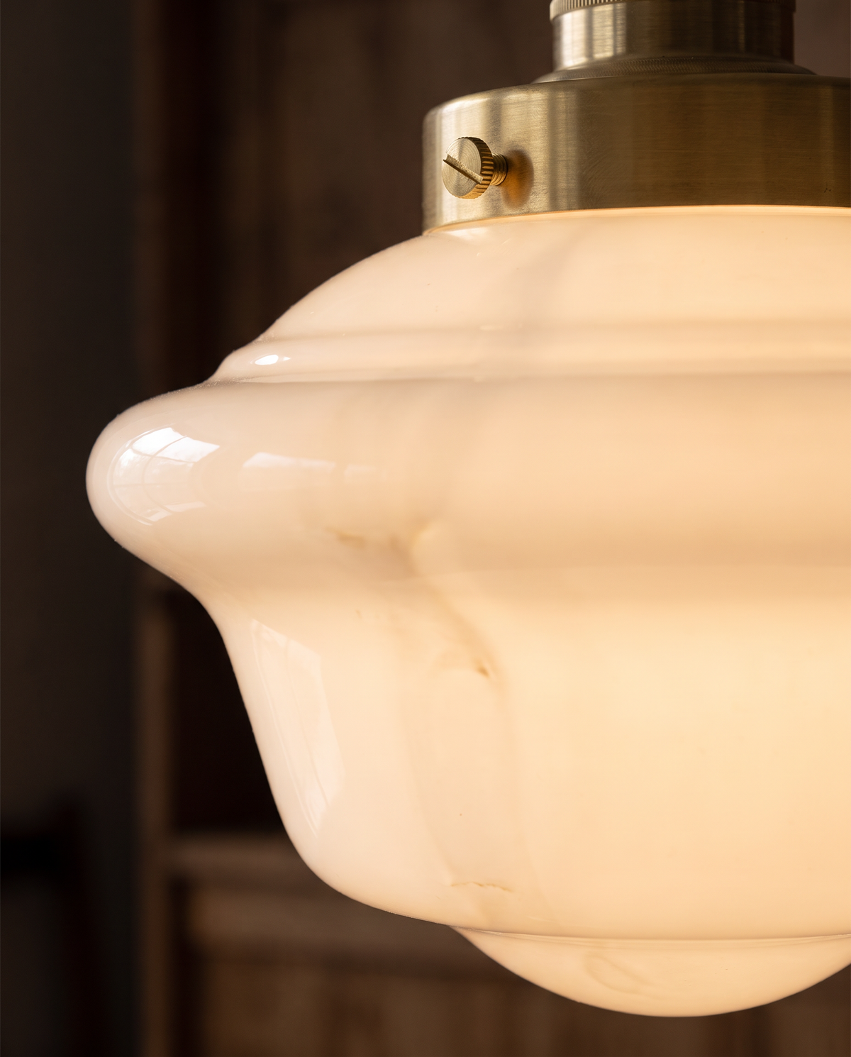 Close-up of the glowing milk opal glass and brass gallery of The Scholar
