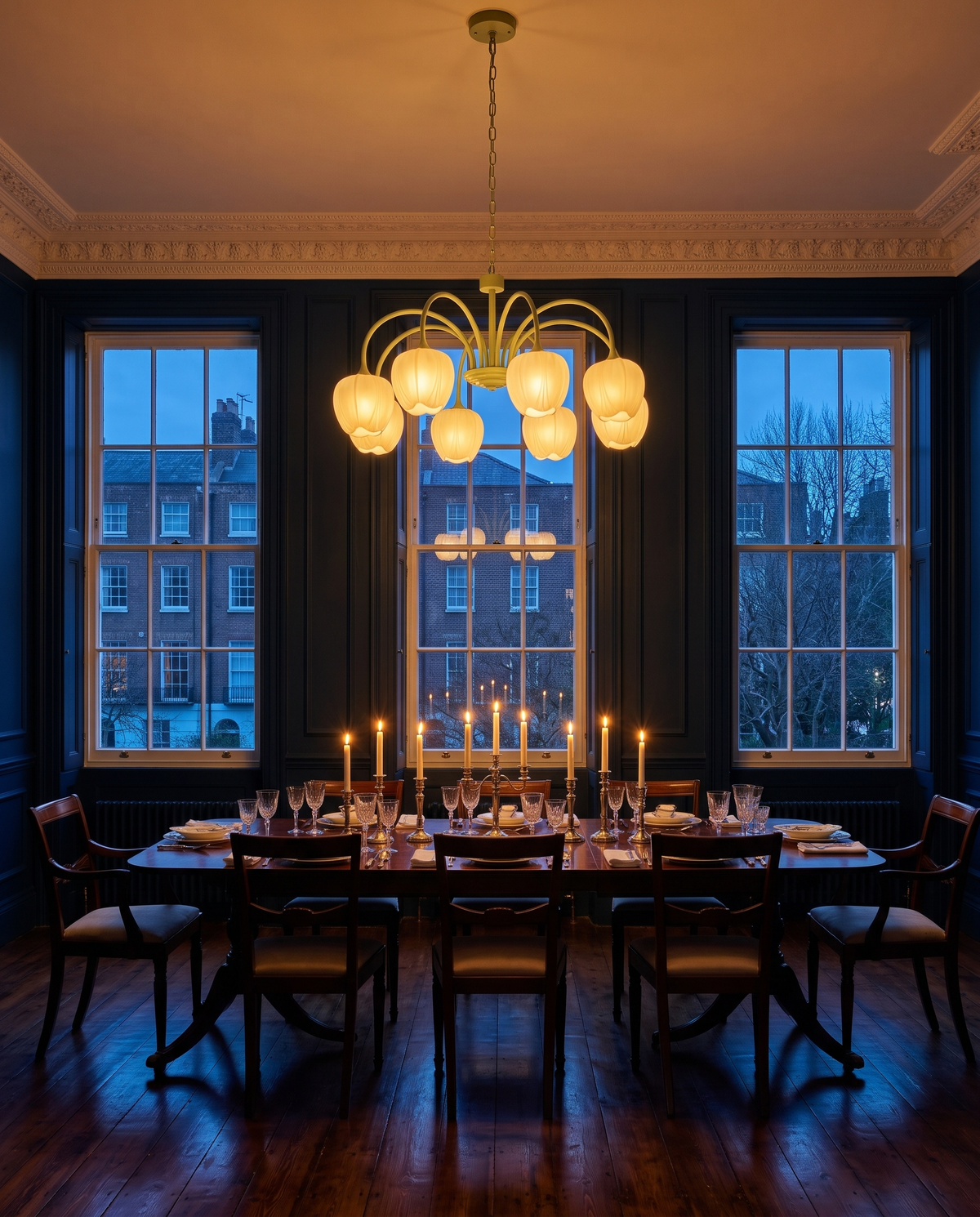 The Snowdrop lit above a candlelit table in an ink-blue dining room at dusk