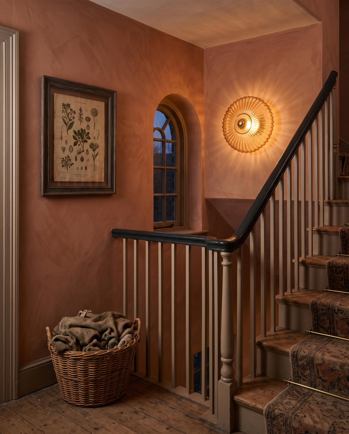 The Sunburst wall light in amber fluted glass on a terracotta staircase landing