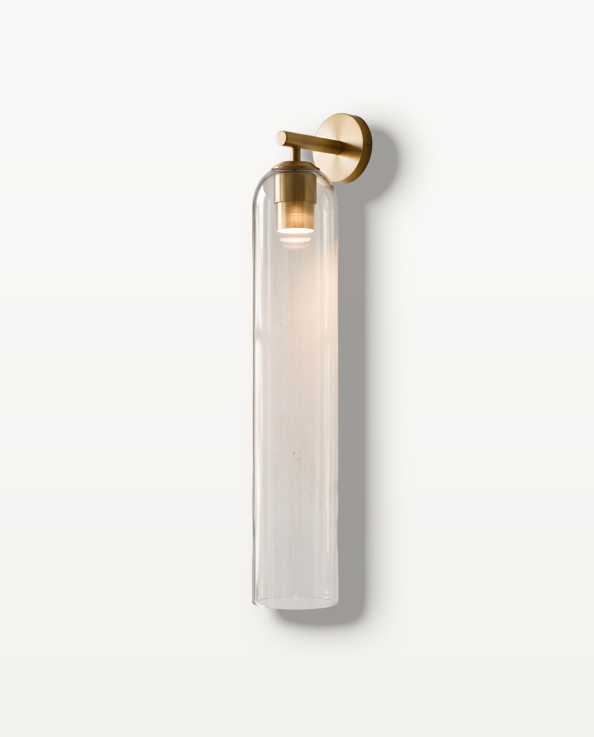 The Taper Wall Light, clear glass, gold finish, lit