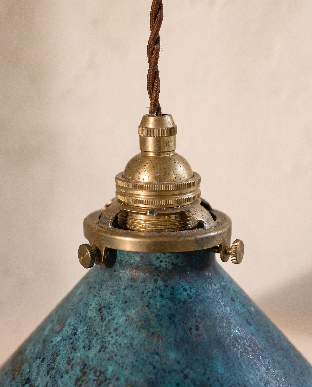 Close-up of the aged brass holder and teal patina of The Tarn