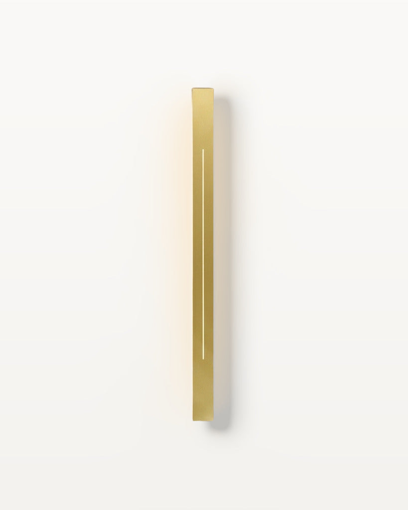 The Beam gold linear LED wall light, lit, on a lime-washed plaster wall — Selden Home product photography
