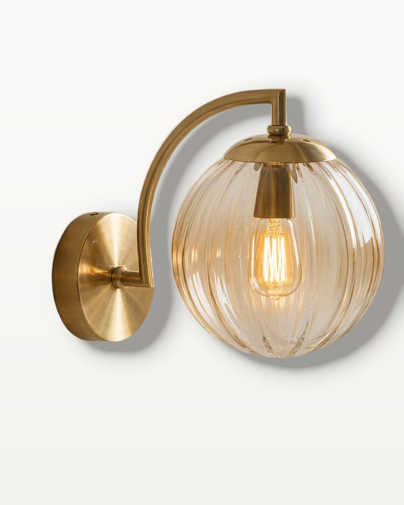 The Bloom, ribbed glass wall sconce, amber glass on gold arm, mounted on plaster wall — Selden Home product photography