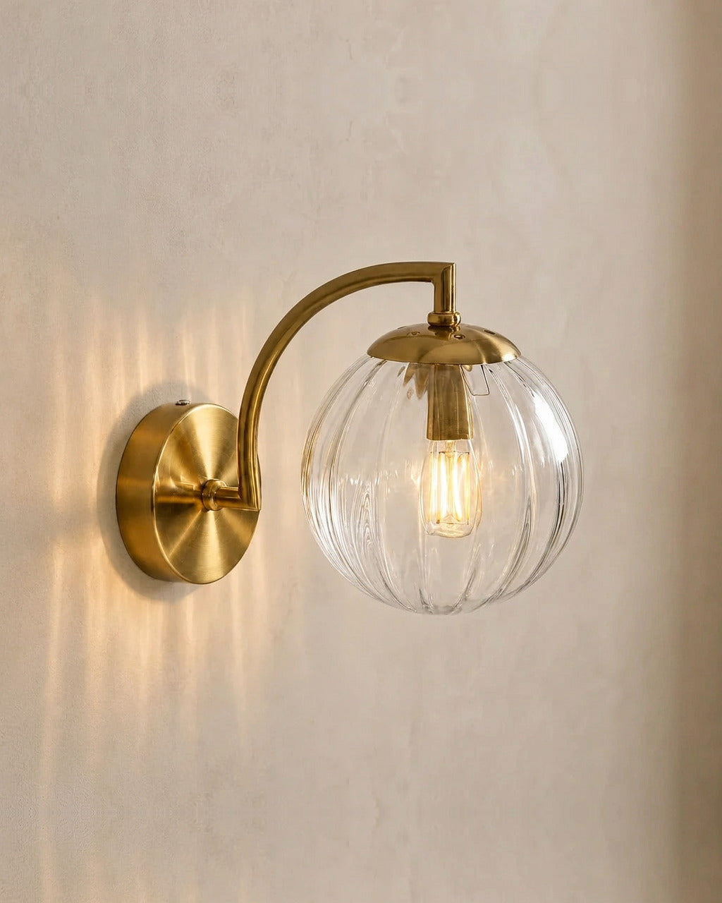 The Bloom, ribbed glass wall sconce, clear glass on gold arm, mounted on plaster wall — Selden Home product photography