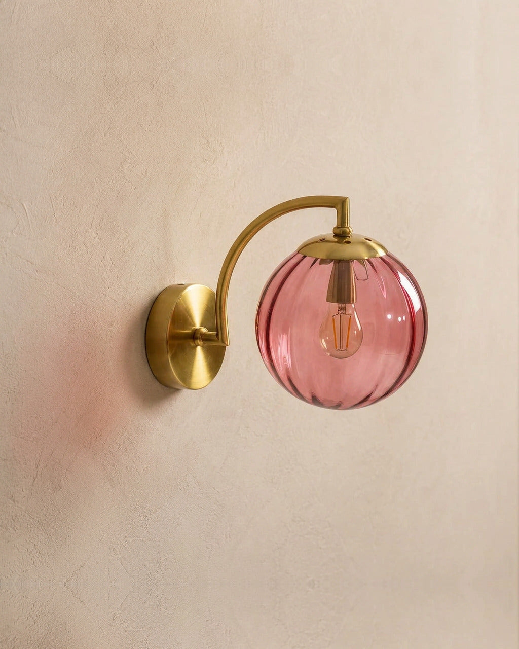 The Bloom, ribbed glass wall sconce, rose red glass on gold arm, mounted on plaster wall — Selden Home product photography