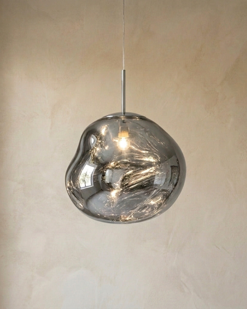 The Ember chrome molten acrylic pendant light with chrome fittings, lit, in front of a lime-washed plaster wall — Selden Home product photography