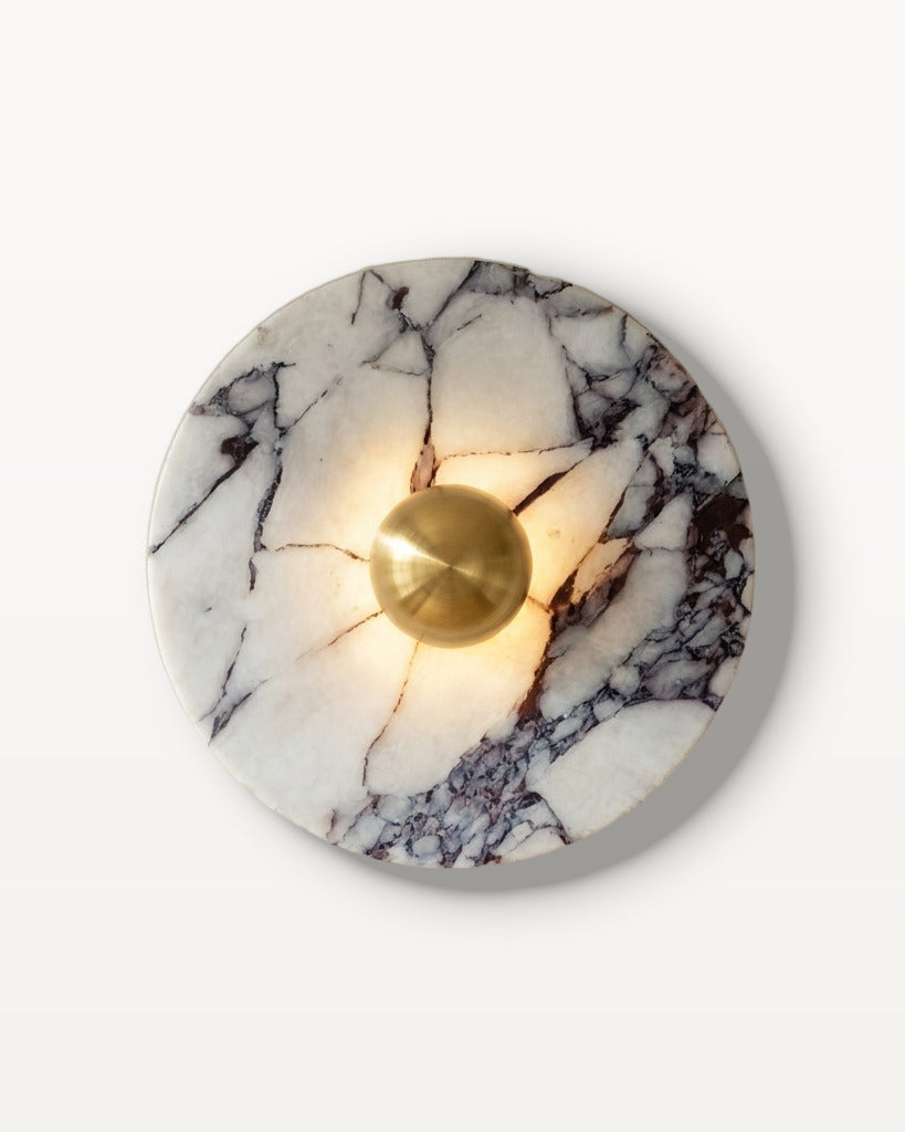 The Orb wall light in gold-tone marble finish, lit, on a lime-washed plaster wall — Selden Home product photography