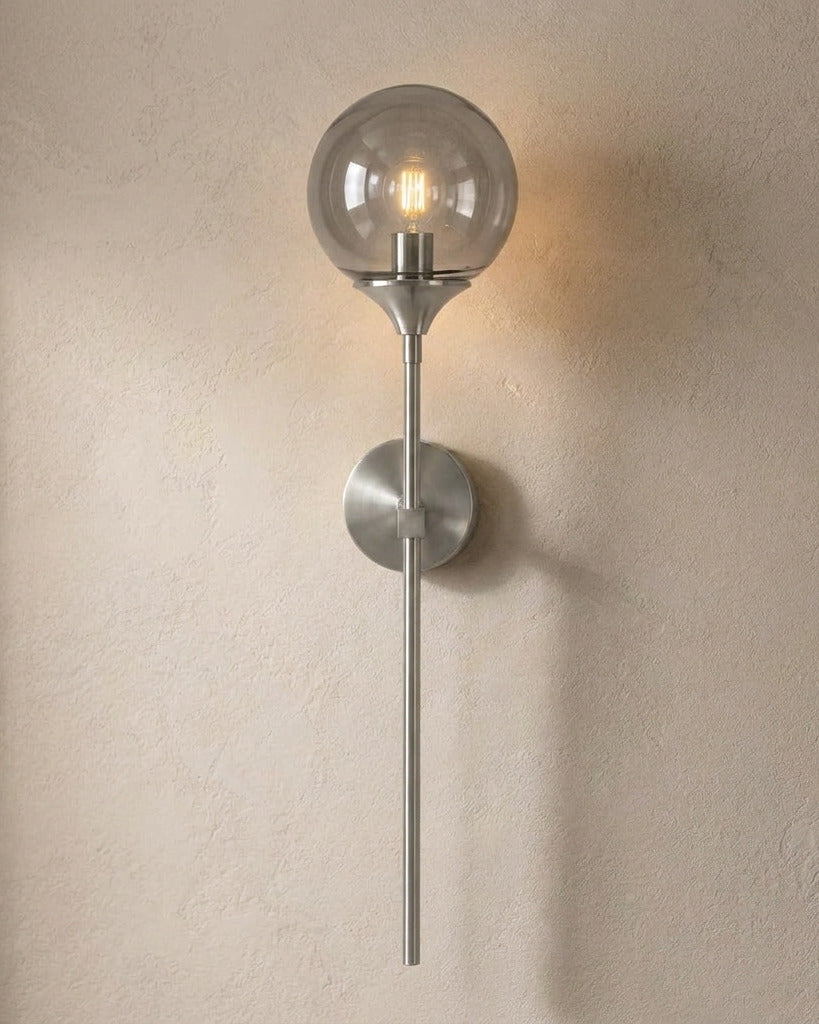 The Reed, silver long-stem wall sconce with smoke grey glass globe, mounted on plaster wall — Selden Home product photography