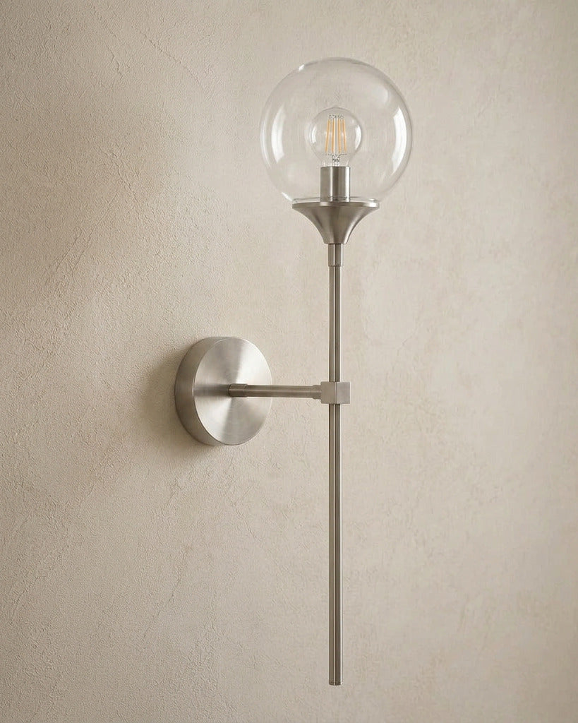 The Reed, silver long-stem wall sconce with clear glass globe, mounted on plaster wall — Selden Home product photography